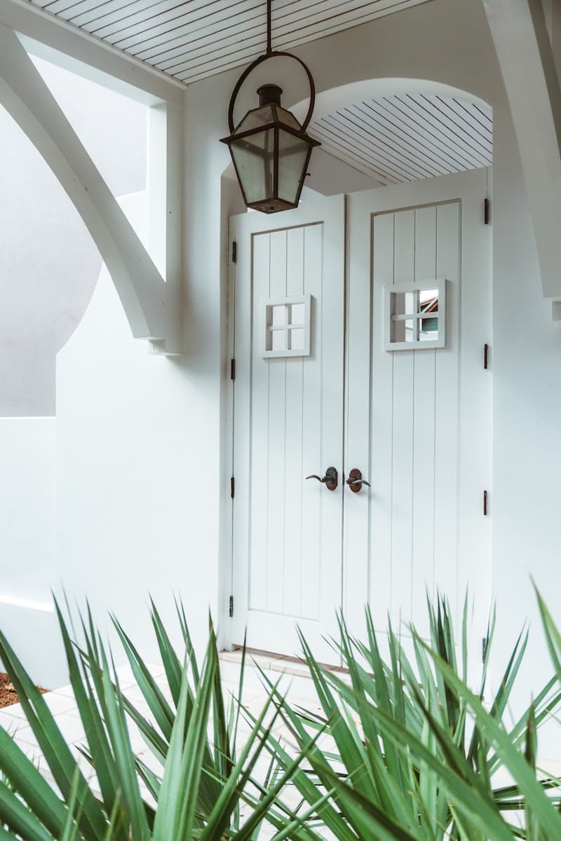 white front door with greenery and hanging lantern