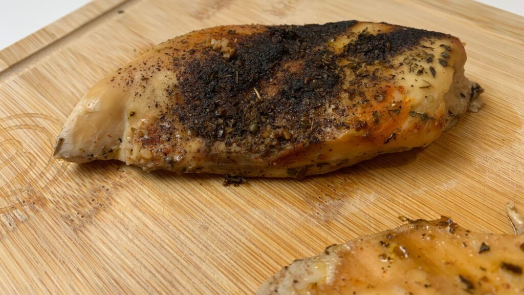 cooked slow cooker chicken breast resting on a cutting board
