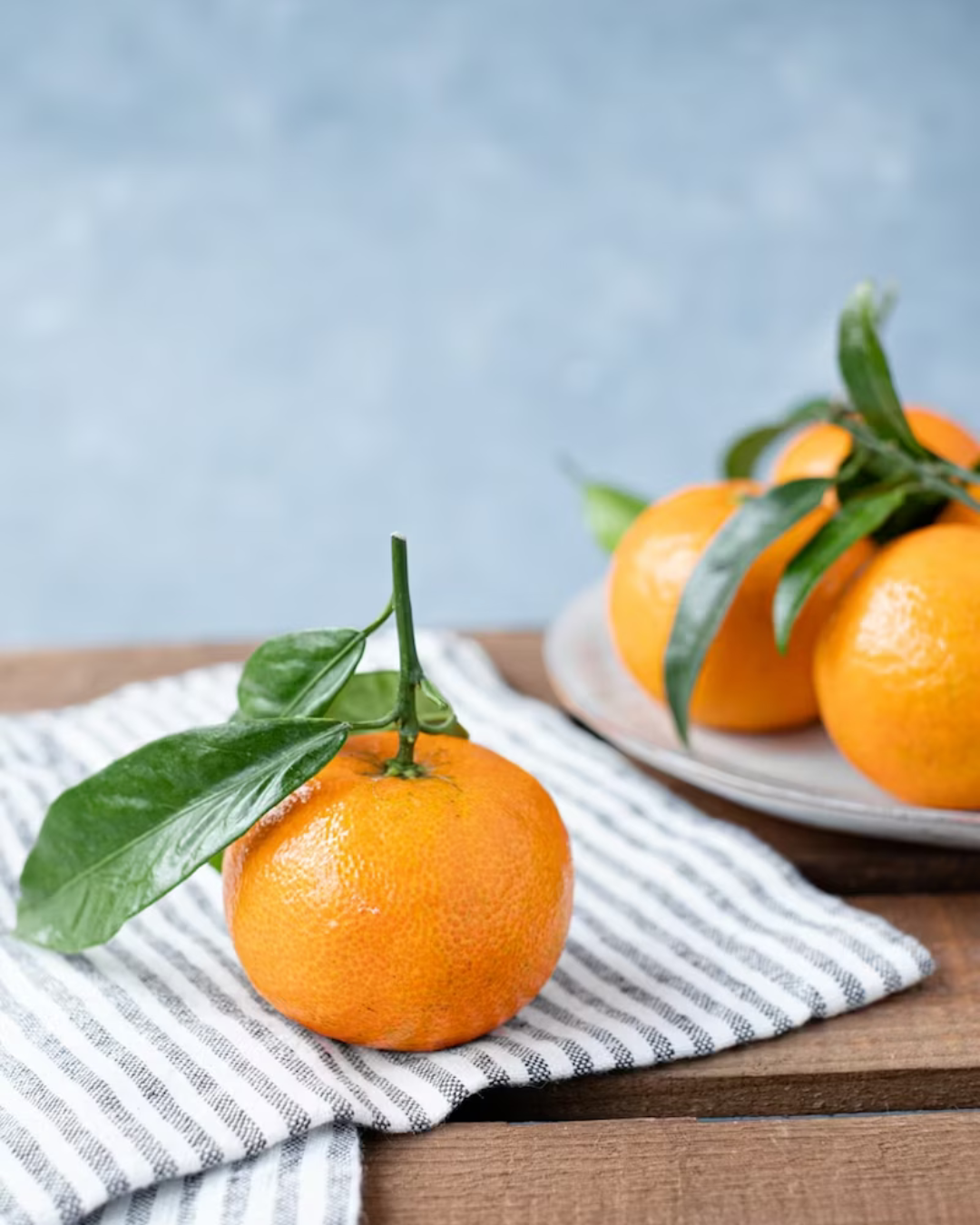 orange with greenery on blue striped napkin and table